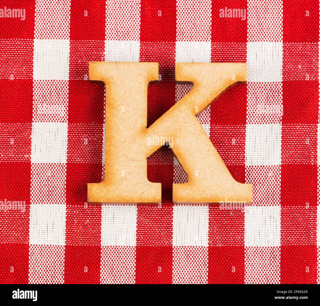 Letter K of the alphabet - Red checkered fabric tablecloth. Stock Photo
