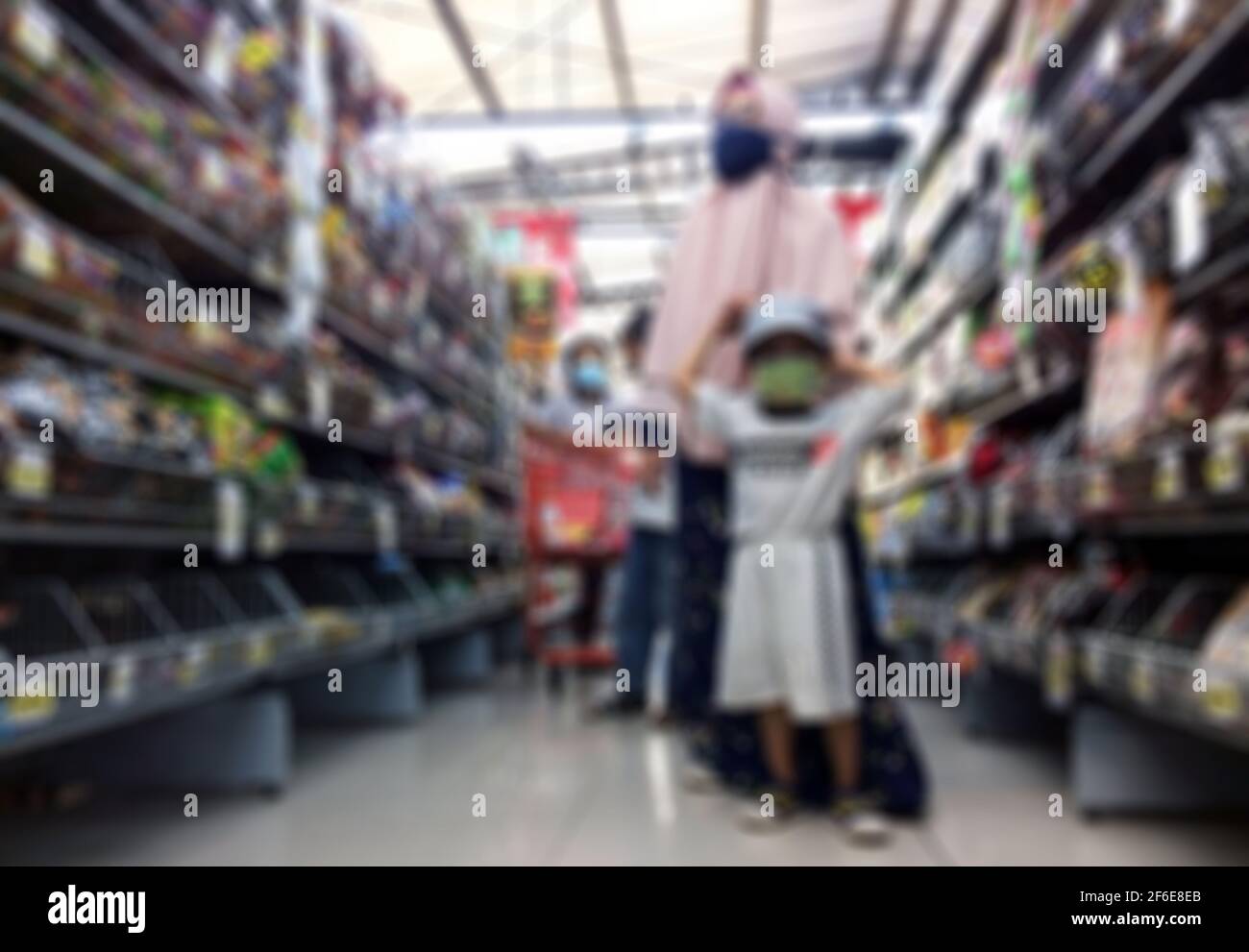 Defocused abstract background of a moslem woman shopper with her child wearing mask to prevent from corona virus at supermarket Stock Photo