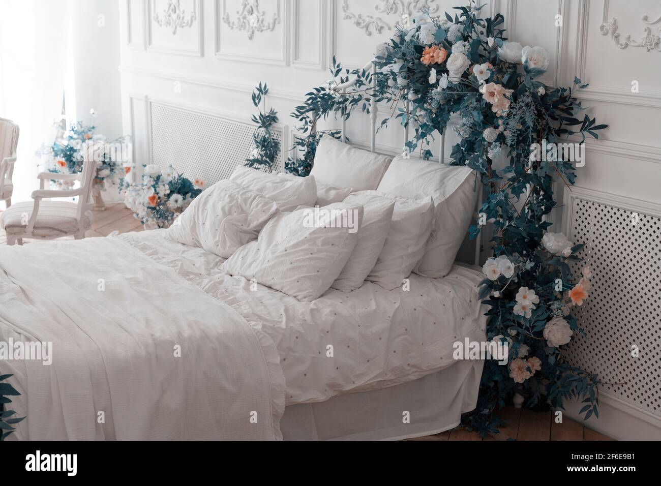 White bedroom. The big comfortable double bed is decorated with magenta  leaves and flowers. Bedroom in soft light colors. Bed of newlyweds Stock  Photo - Alamy