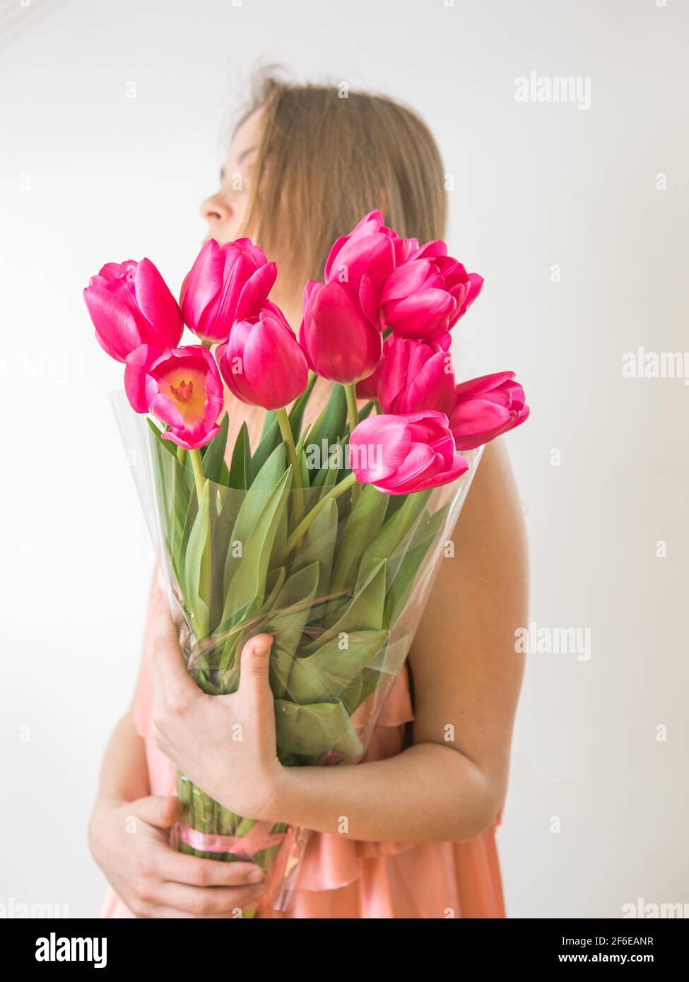 Portrait of a beautiful young girl in dress holding big bouquet of ...