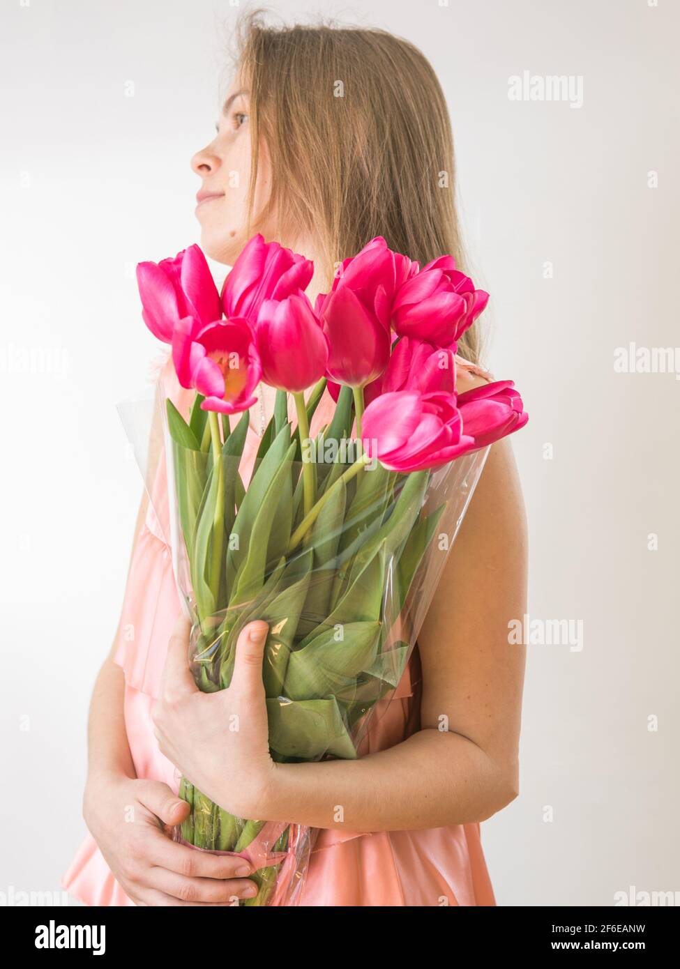 Portrait of a beautiful young girl in dress holding big bouquet of ...