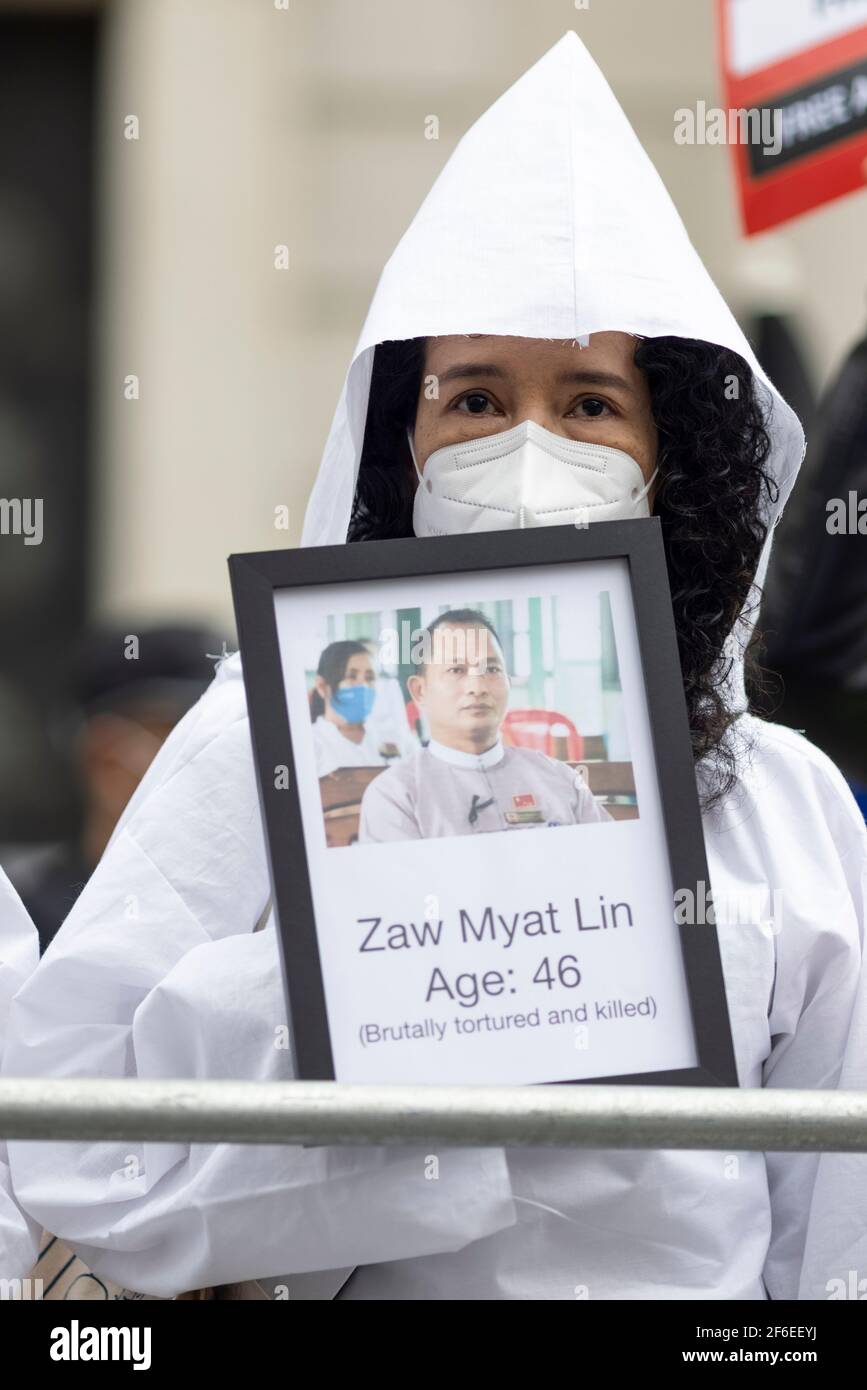 London, UK. 31st Mar, 2021. A female protester dressed in white holding a photograph of a deceased victim outside the Chinese Embassy. Protesters gathered in Parliament Square - wearing face masks and observing social-distancing - before marching to the Chinese Embassy in solidarity with the people of Myanmar against the military coup and state killings of civilians. Speeches were given outside the embassy. Since the beginning of the military coup on the 1st of February over 520 people have been killed in Myanmar by security forces. Last Saturday was the most violent day when more than 100 peo Stock Photo