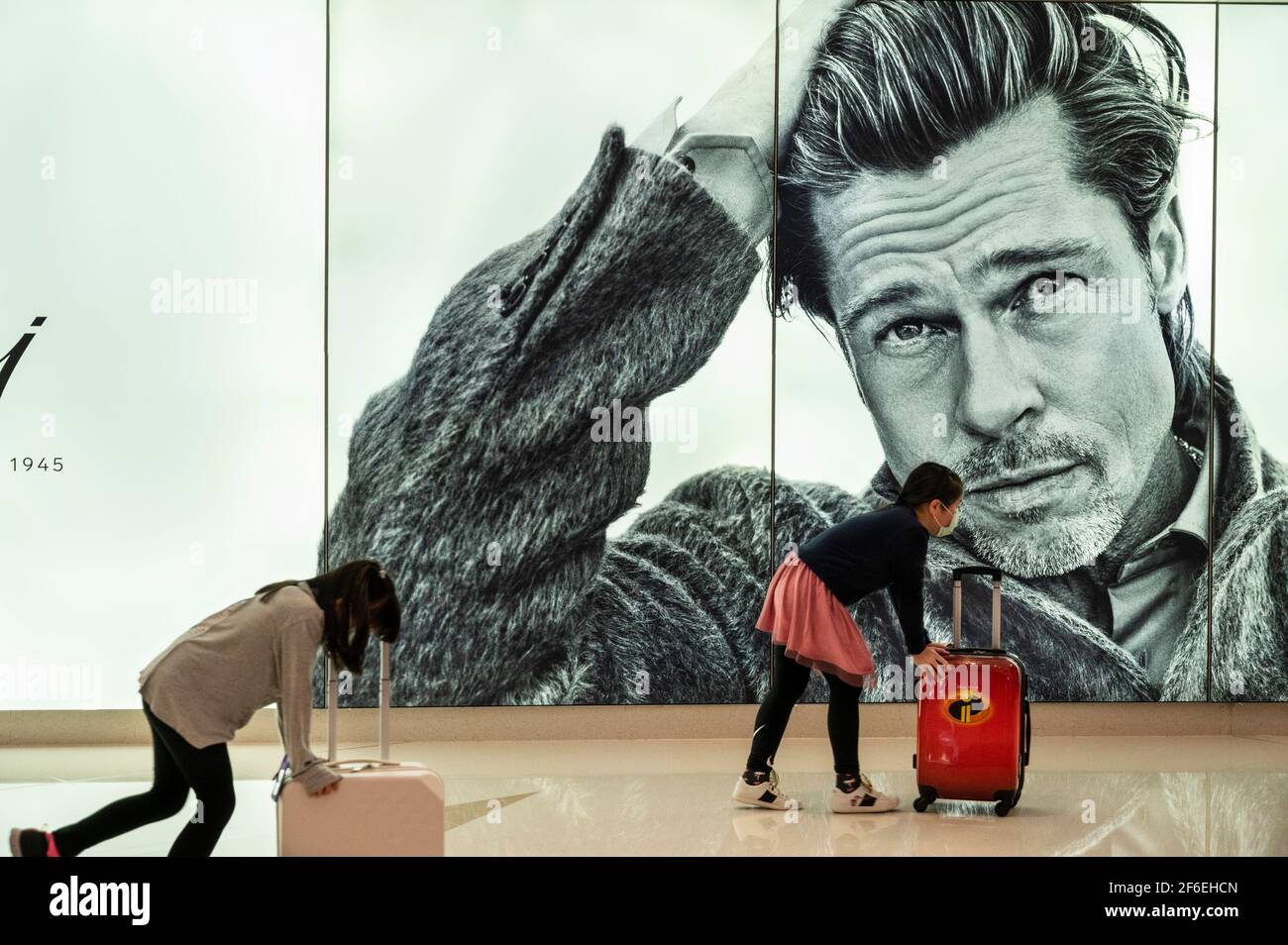 Hong Kong, China. 31st Mar, 2021. Children run past a large commercial ad  of Italian luxury tailor fashion brand Brioni brand displaying its brand  ambassador the American actor Brad Pitt seen in