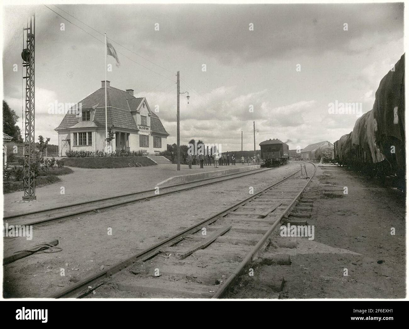 View at Dalsjöfors.To Right arriving luminous wagons. The station designed by architect Rudolf Lange and opened in 1917. One and one-high volume plastered station houses. In 1936, waiting room and expedition were remodeled. Avbanned from the end of the year 1974/75, 1980 down-marked as a stop. The station house was revolved in the summer of 1982. The station house was replaced after the demolition of an open bus Stock Photo