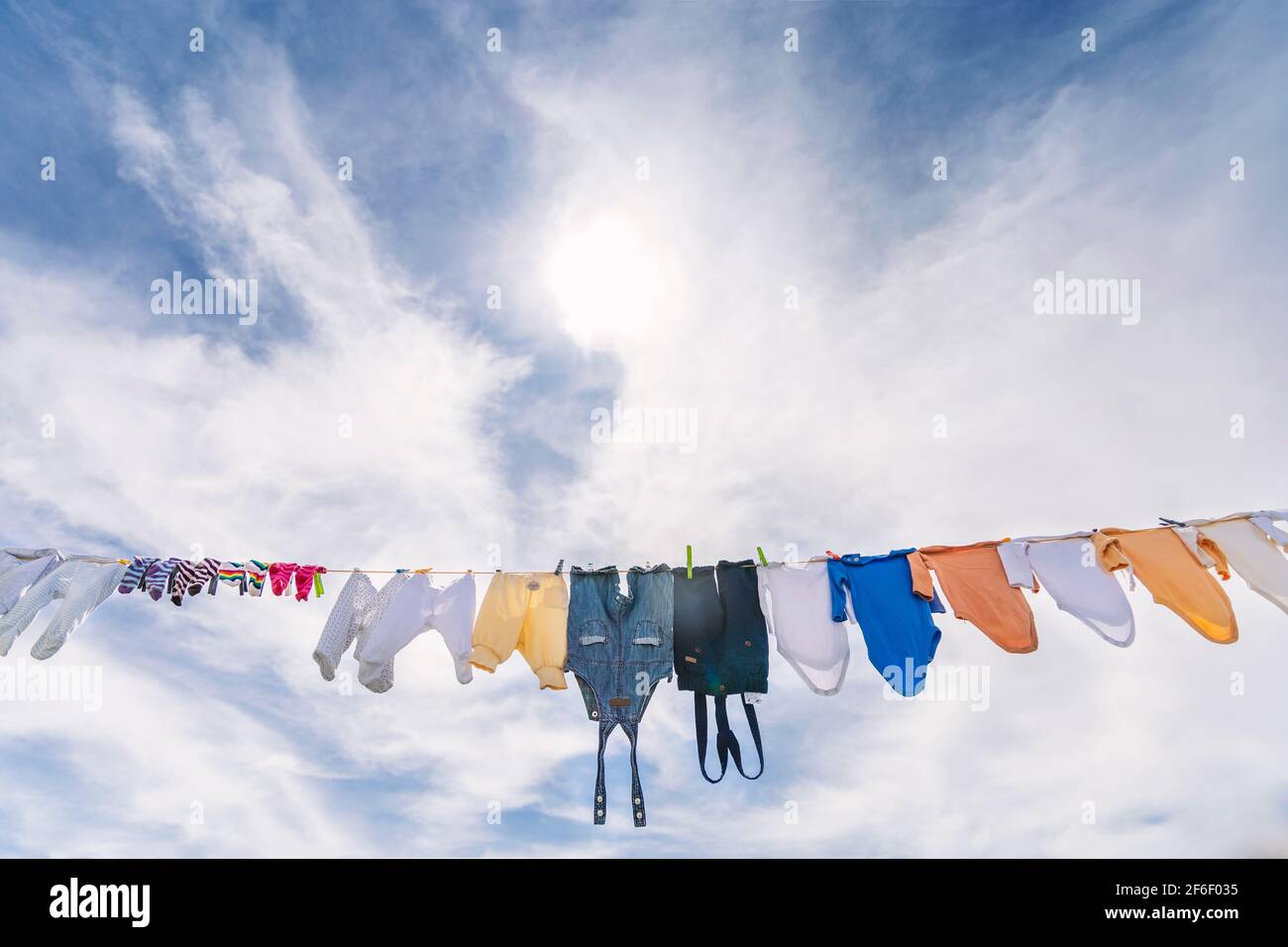 A lot of small baby clothes hanging  against blue cloudy sky Stock Photo