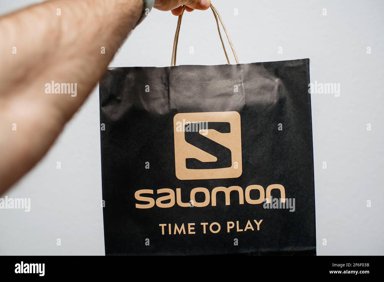 POV male hand holding black paper bag package Salomon Time to play fashion  brand printed Stock Photo - Alamy