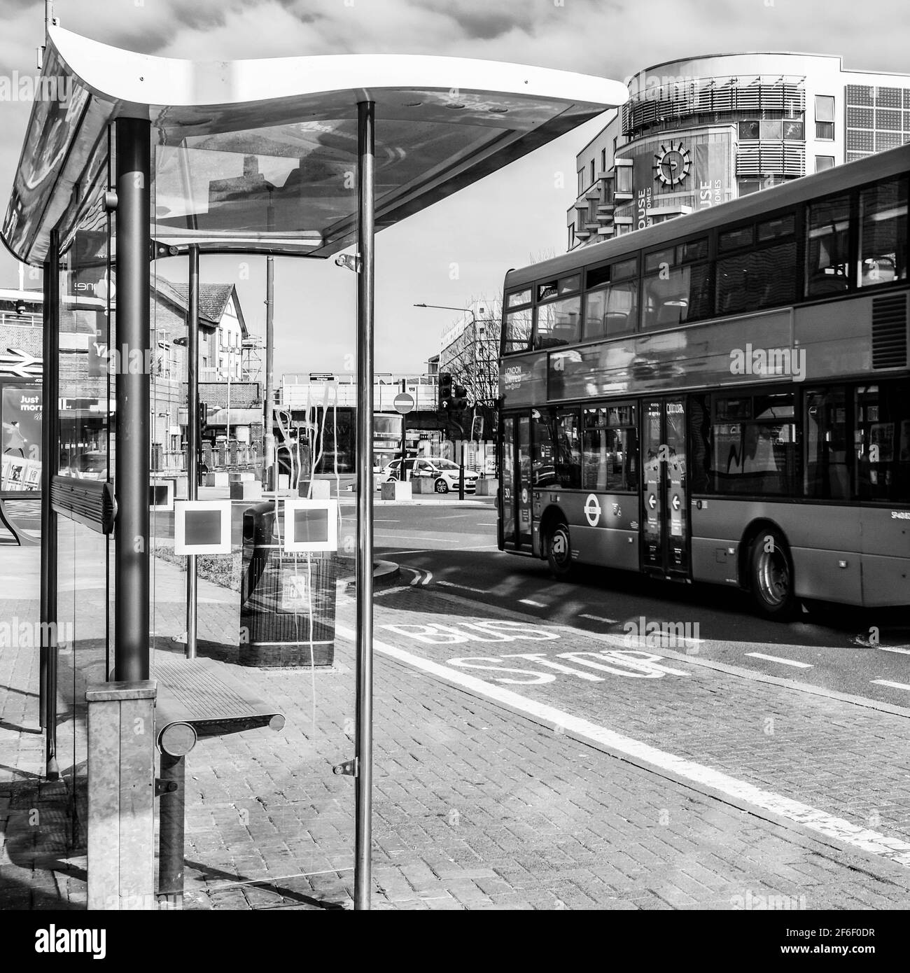 Black And White Image Of A Modern Designed Public Bus Shelter Or Stop With A Passing Bus And No People Stock Photo