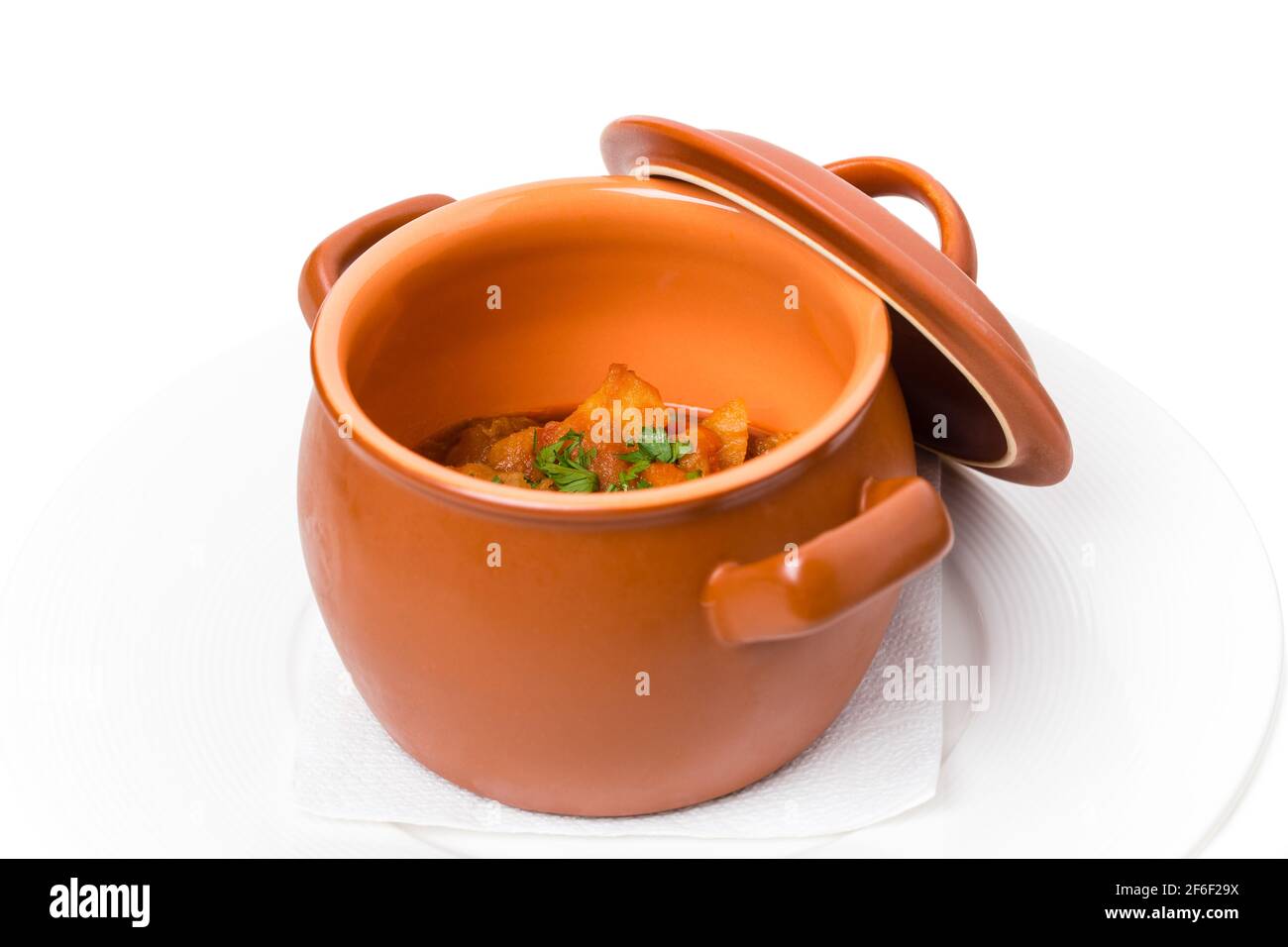 Stewed pork and potatoes covered with minced herbs in crock pot