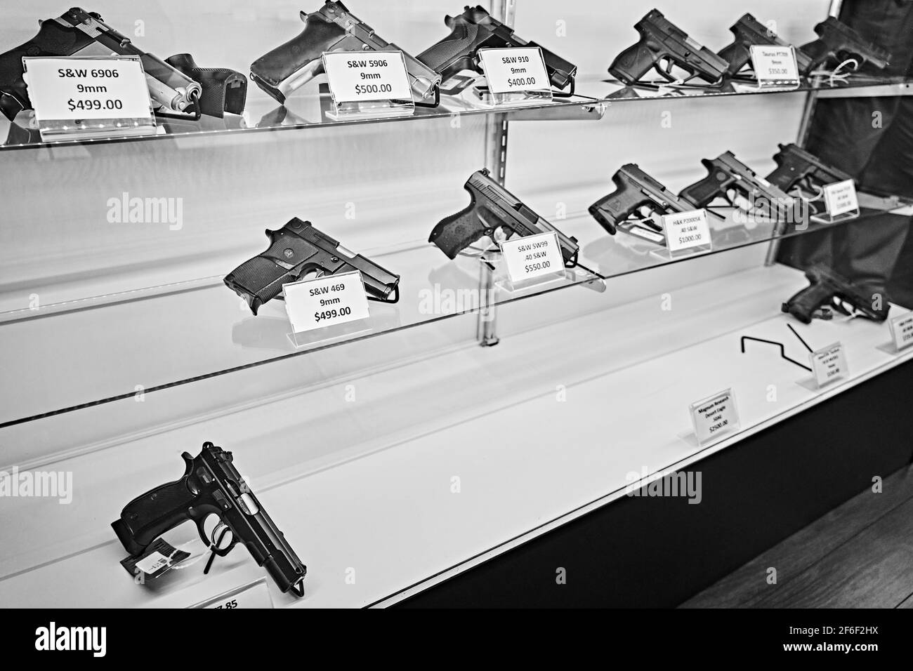 Handguns with labels and price tags on sale on shelves at gun store with many pistols already sold out. USA Stock Photo