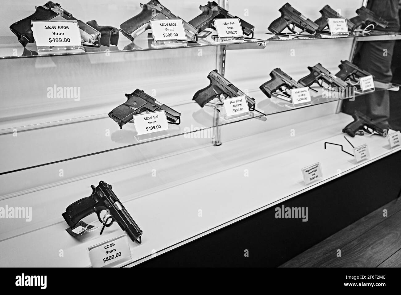 Handguns with labels and price tags on sale on shelves at gun store with many pistols already sold out. USA Stock Photo