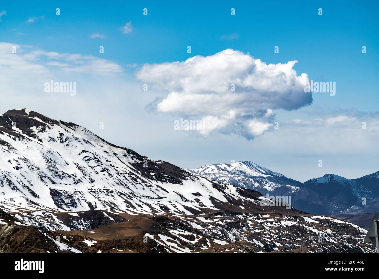 Cloud over snow capped mountain peaks Stock Photo - Alamy