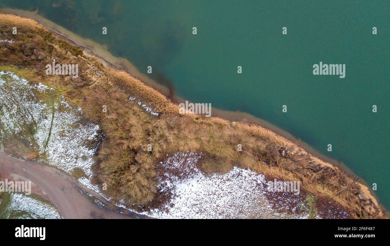 Aerial view of the winter snow covered forest and frozen lake from ...