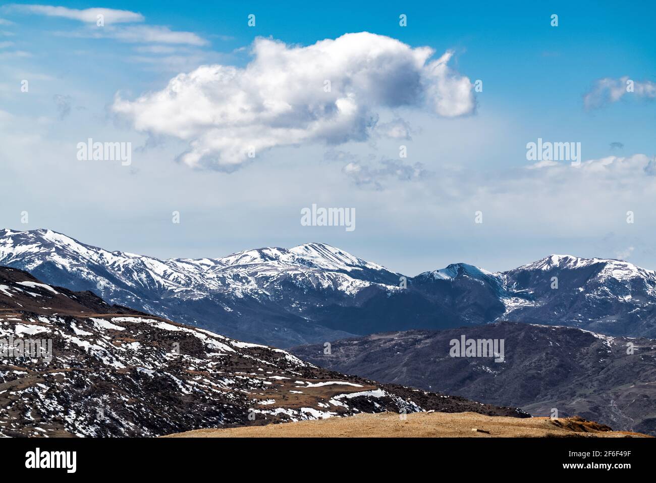 Cloud over snow capped mountain peaks Stock Photo - Alamy