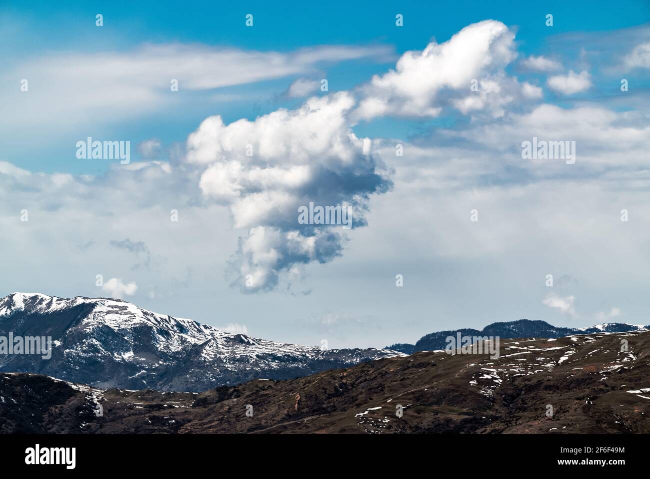 Cloud over snow capped mountain peaks Stock Photo - Alamy