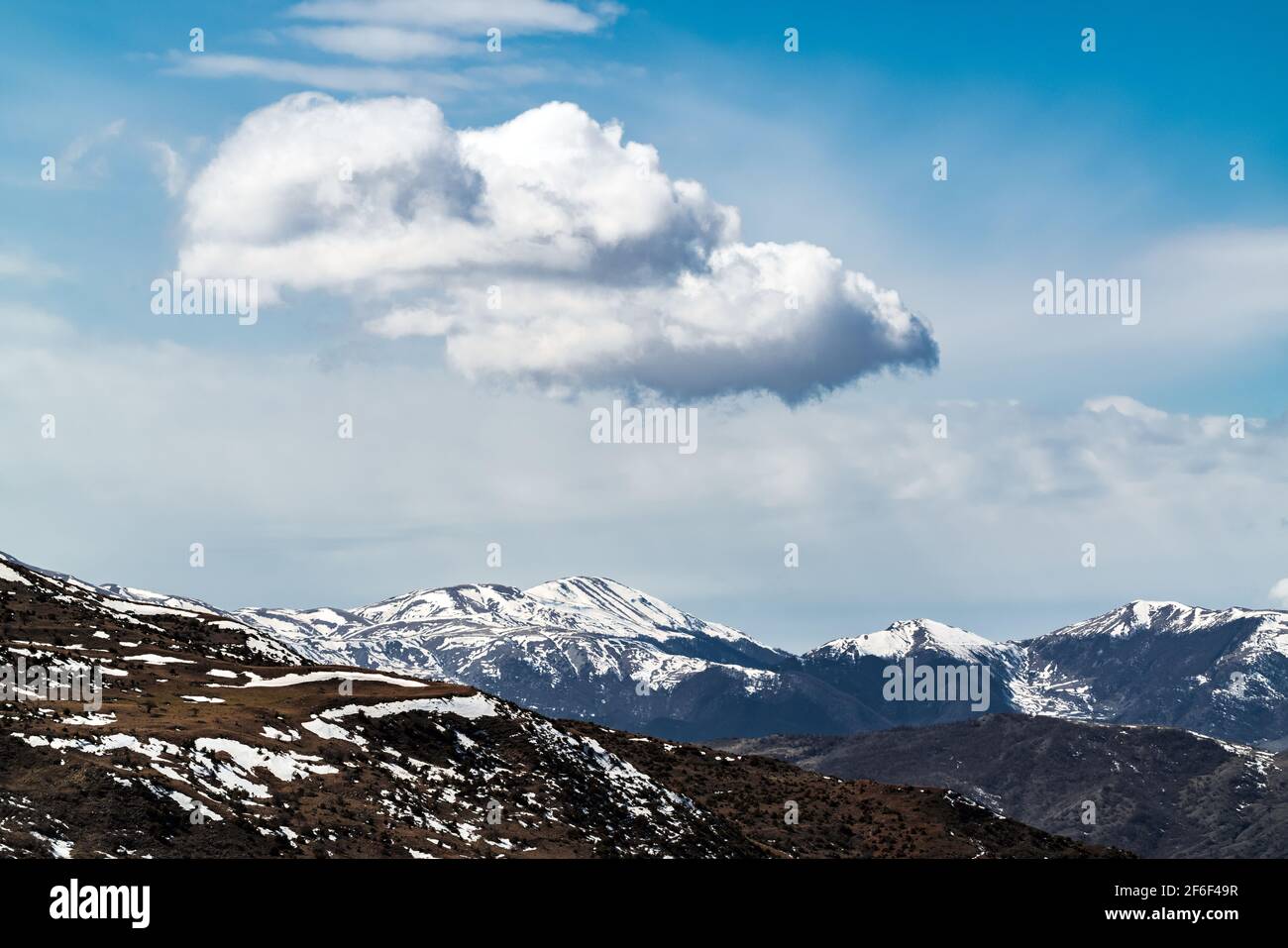 Cloud over snow capped mountain peaks Stock Photo - Alamy