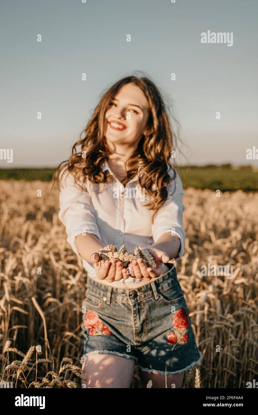 Wheat crop, harvest, Harvesting agriculture, economy. Young brunette woman with hands full of ripe wheat seeds in cereal field ready harvest Stock Photo