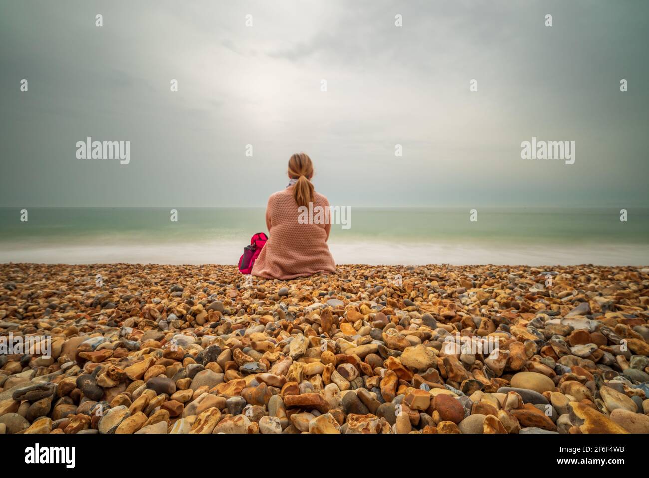 Woman sitting on a beach and looking at the sea Stock Photo - Alamy