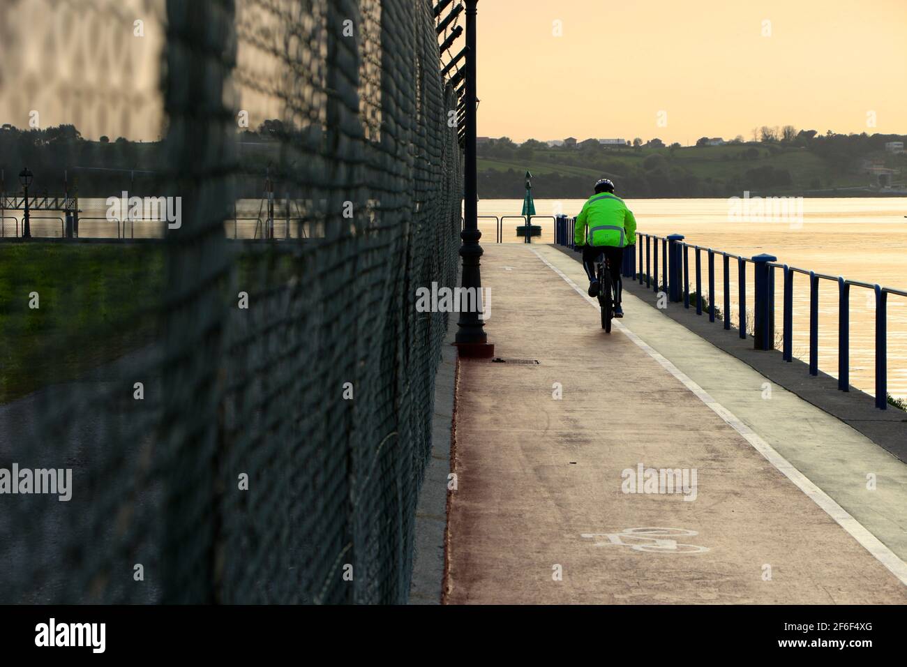 Cyclist following the security fence on a cycle path around Seve Ballesteros Santander airport next to the bay Santander Cantabria Spain Spring Stock Photo