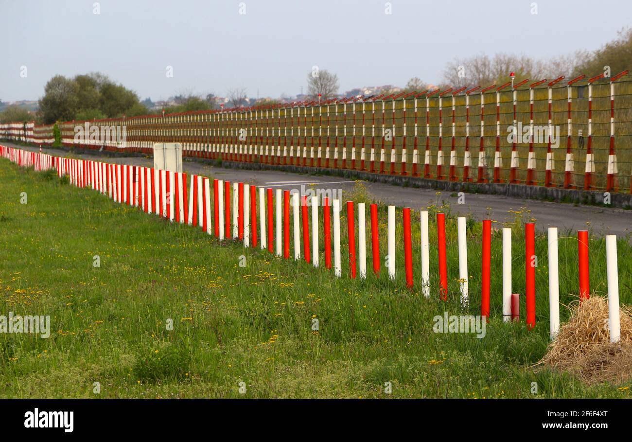 Metal security fence diminishing perspective red and white at the Seve Ballesteros International Airport Santander Cantabria Spain in morning sun Stock Photo