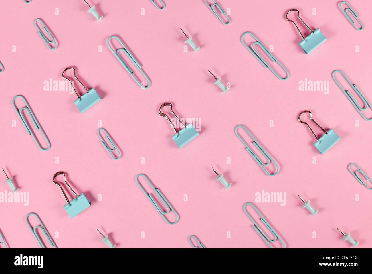 Stationery items like paper clips and drawing pins arranged on pink background Stock Photo