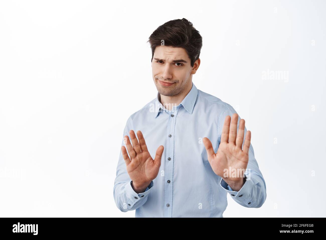 Slow down, stop, stay away, keep social distance. Skeptical boss, male entrepreneur showing refuse, reject block gesture, telling to quit, standing Stock Photo