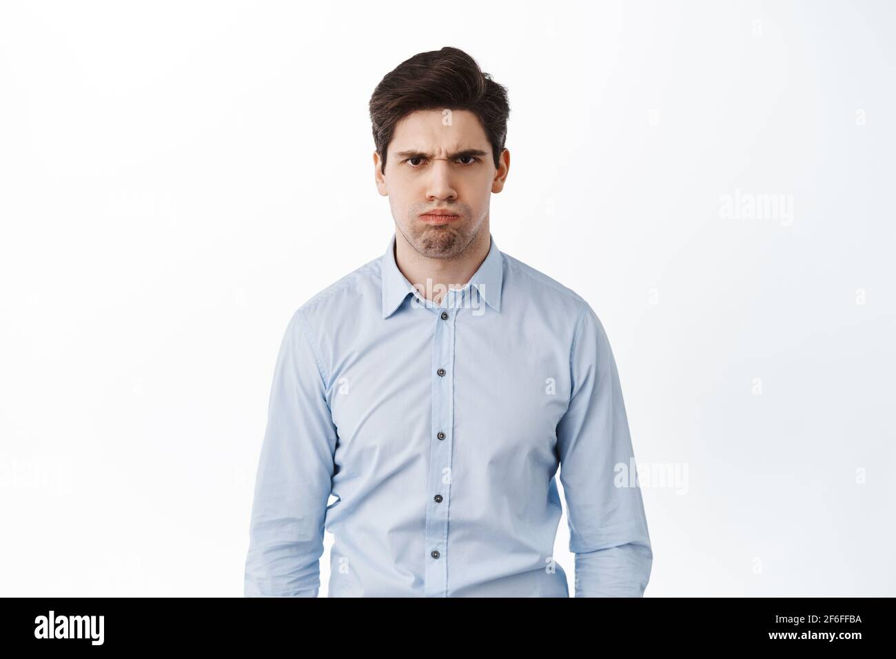 Angry and displeased office worker, frowning and looking mad, standing bothered or insulted, losing temper, boiling from anger, standing over white Stock Photo