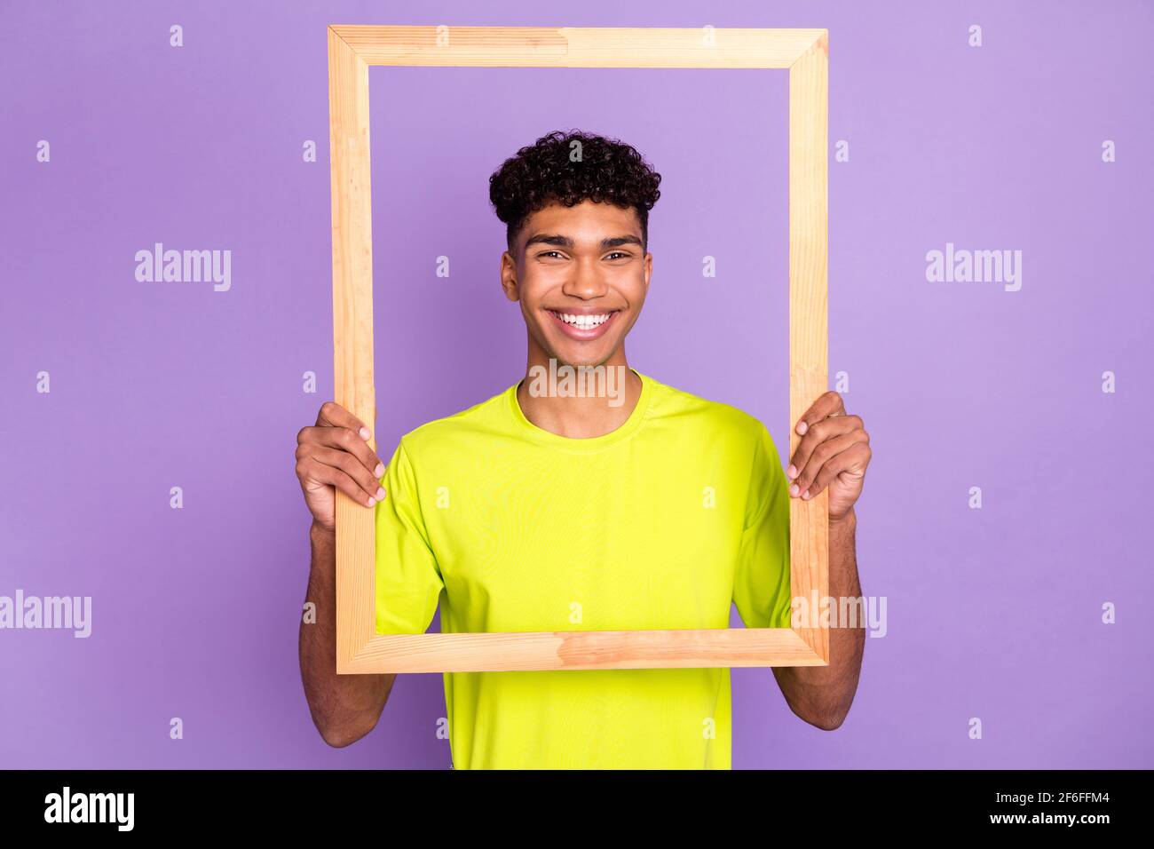 Photo of young cheerful afro man happy positive smile hold wood frame border photographing isolated over violet color background Stock Photo