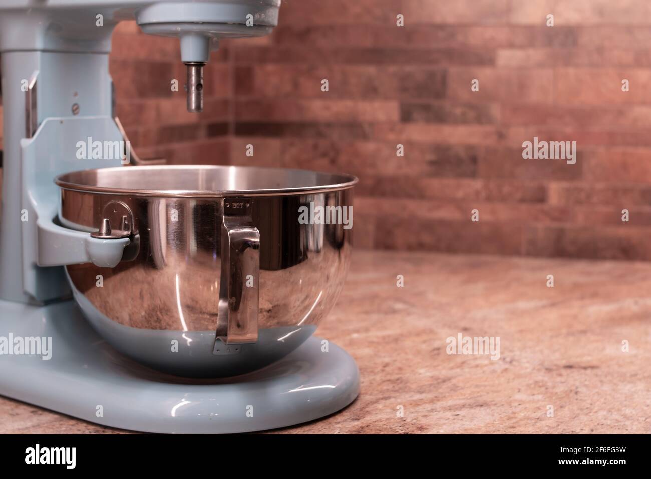 Turquoise stand mixer against a terracotta tile backsplash, set on a marble kitchen countertop. Stock Photo