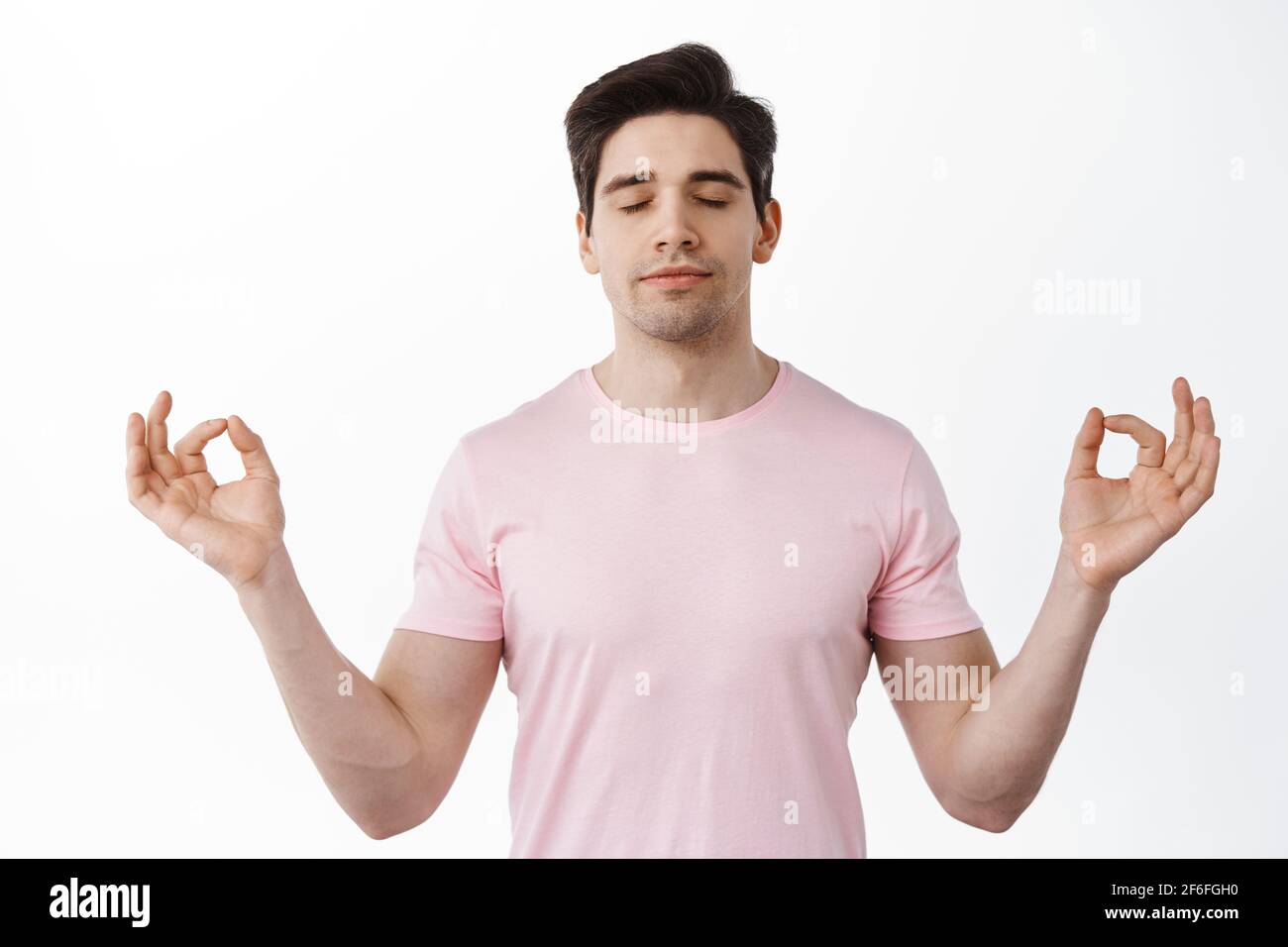 Relaxed and calm man meditating, standing in zen lotus pose with om