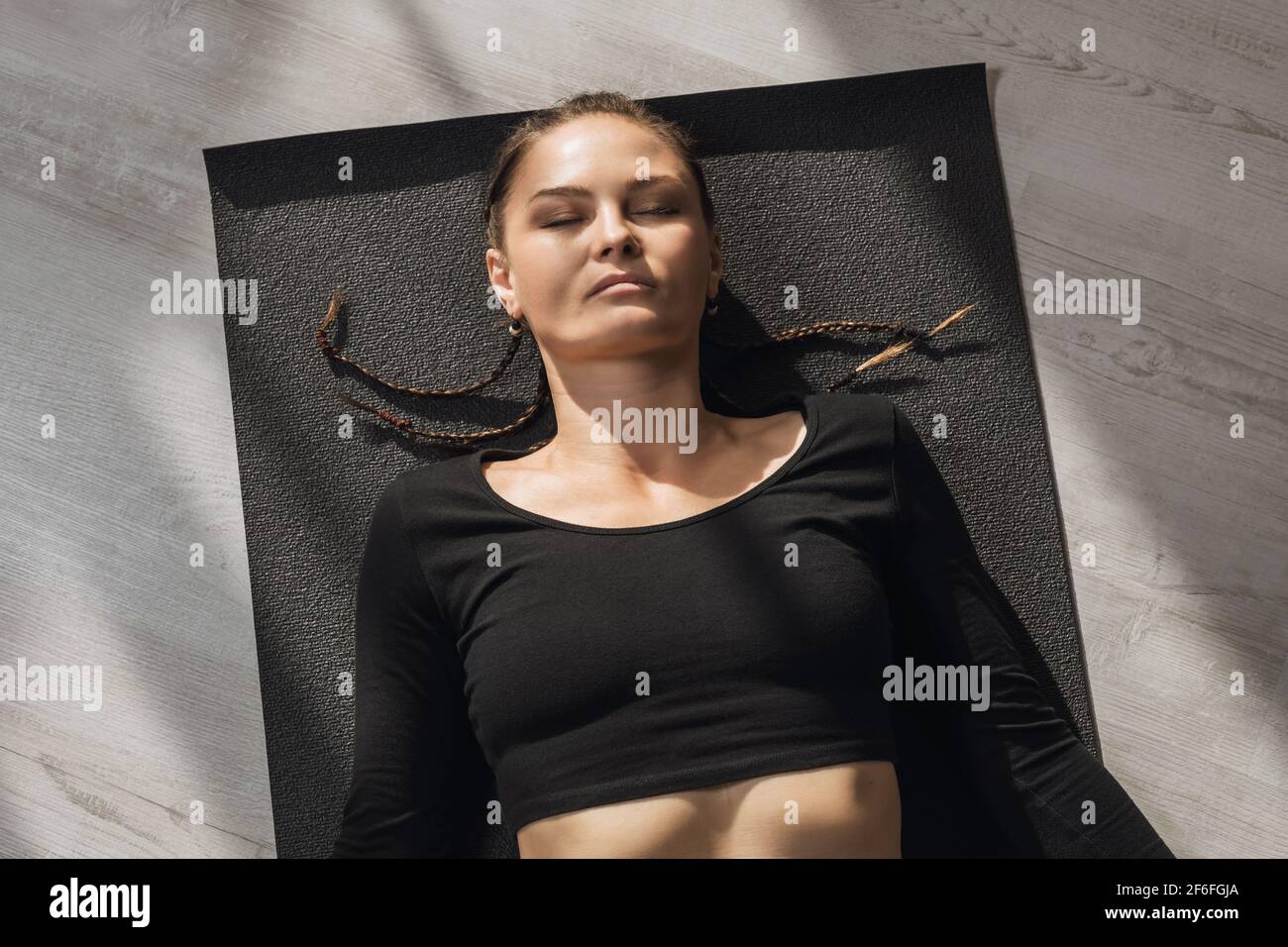 Woman practicing yoga, resting after training, performing shavasana exercise, top view. Stock Photo