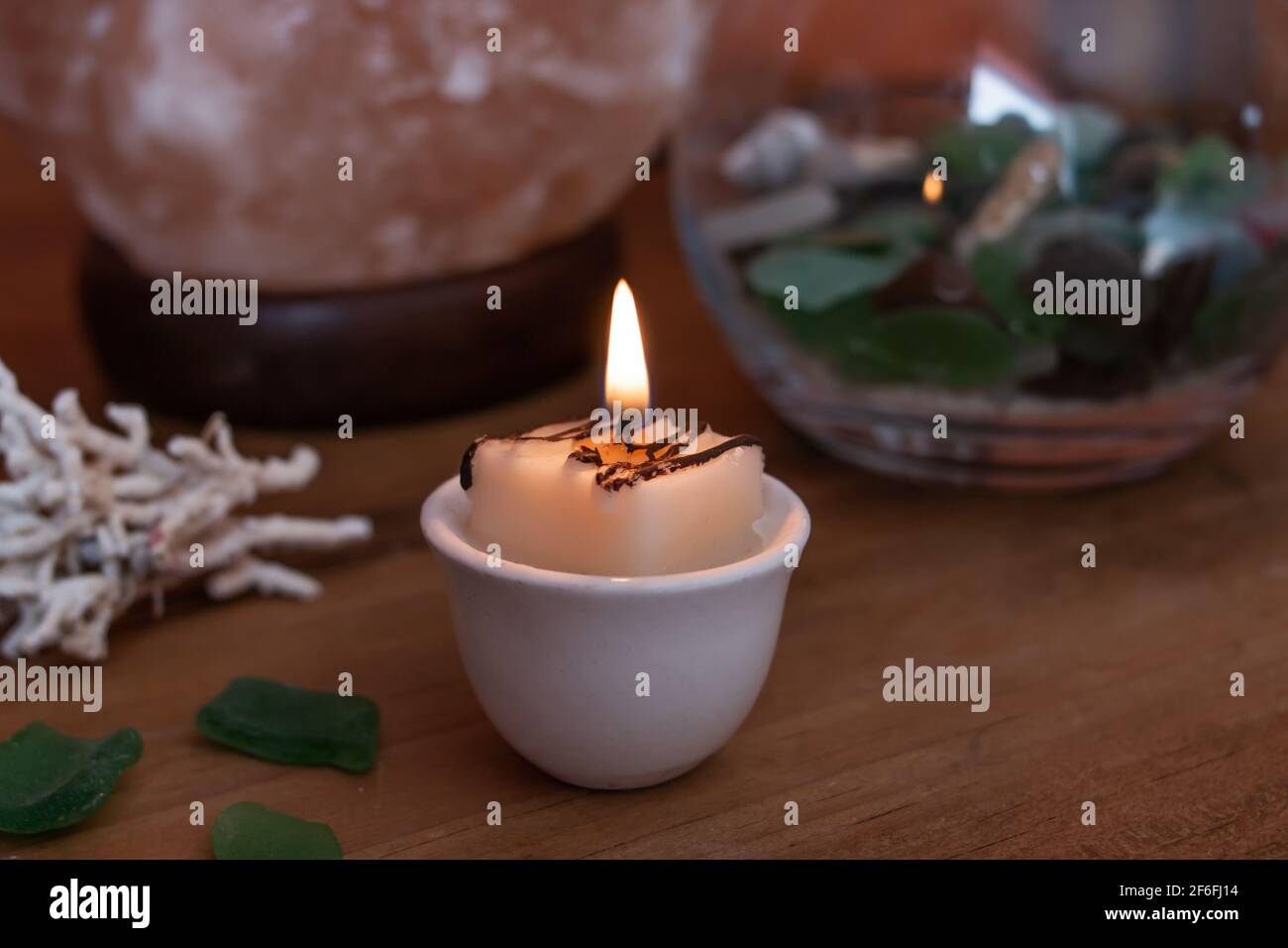 Vintage tea light setup, candle surrounded by a salt lamp, sea glass and coral, Ontario, Canada, faintly glowing, 2021. Stock Photo