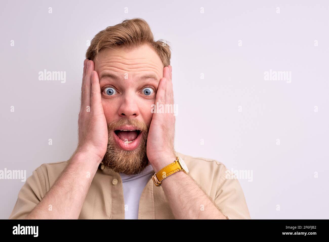 close-up portrait of shocked bearded man standing with wide opened ...