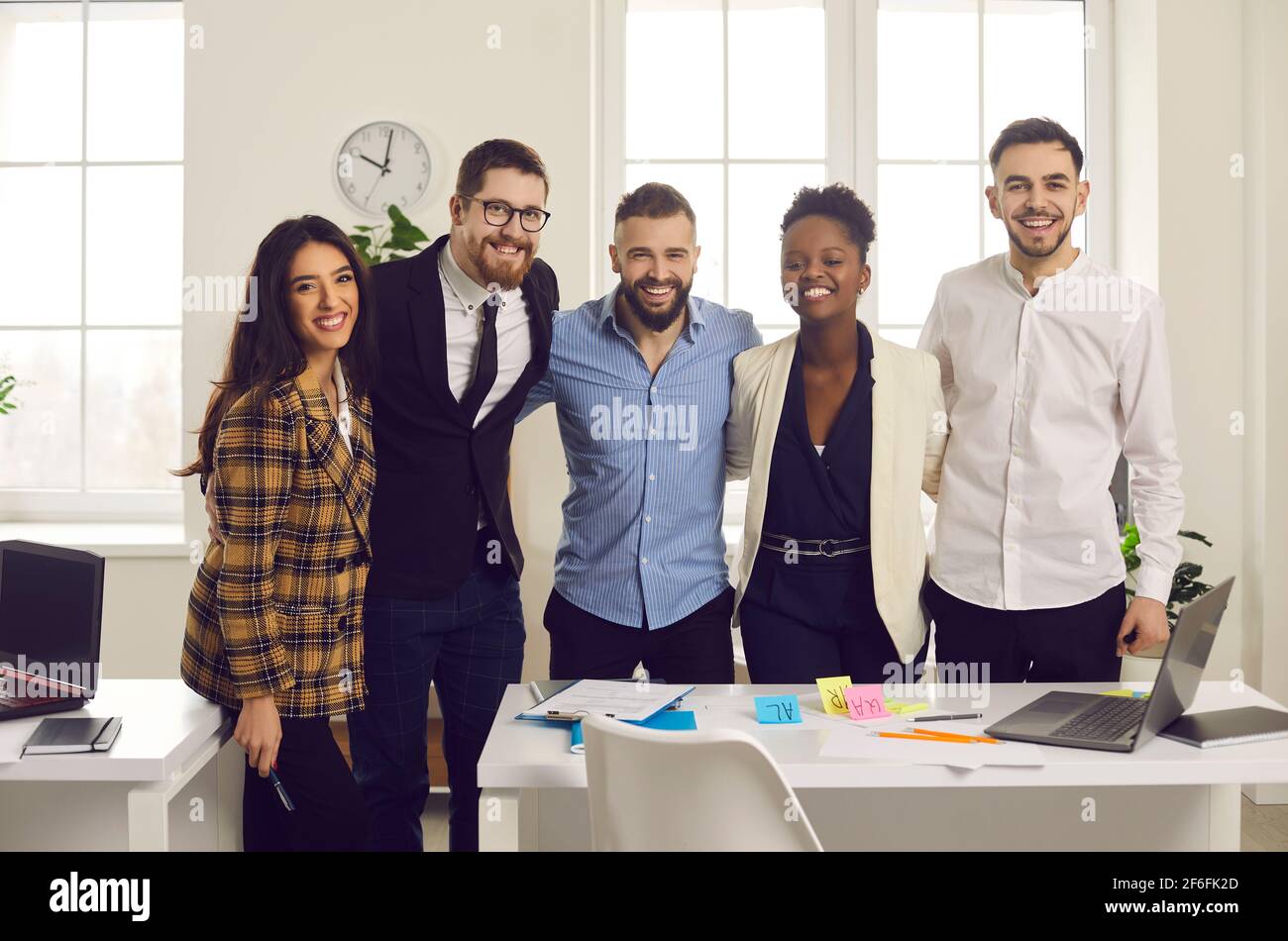 Positive smiling diverse business team hugging looking at camera in ...