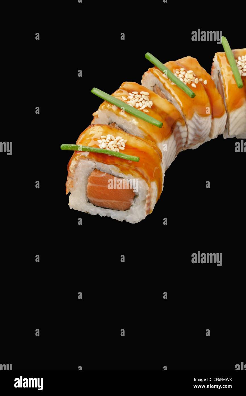 Sushi roll with salmon, eel, Japanese mayonnaise, unagi sauce, sesame  seeds. Isolated over black background Stock Photo - Alamy