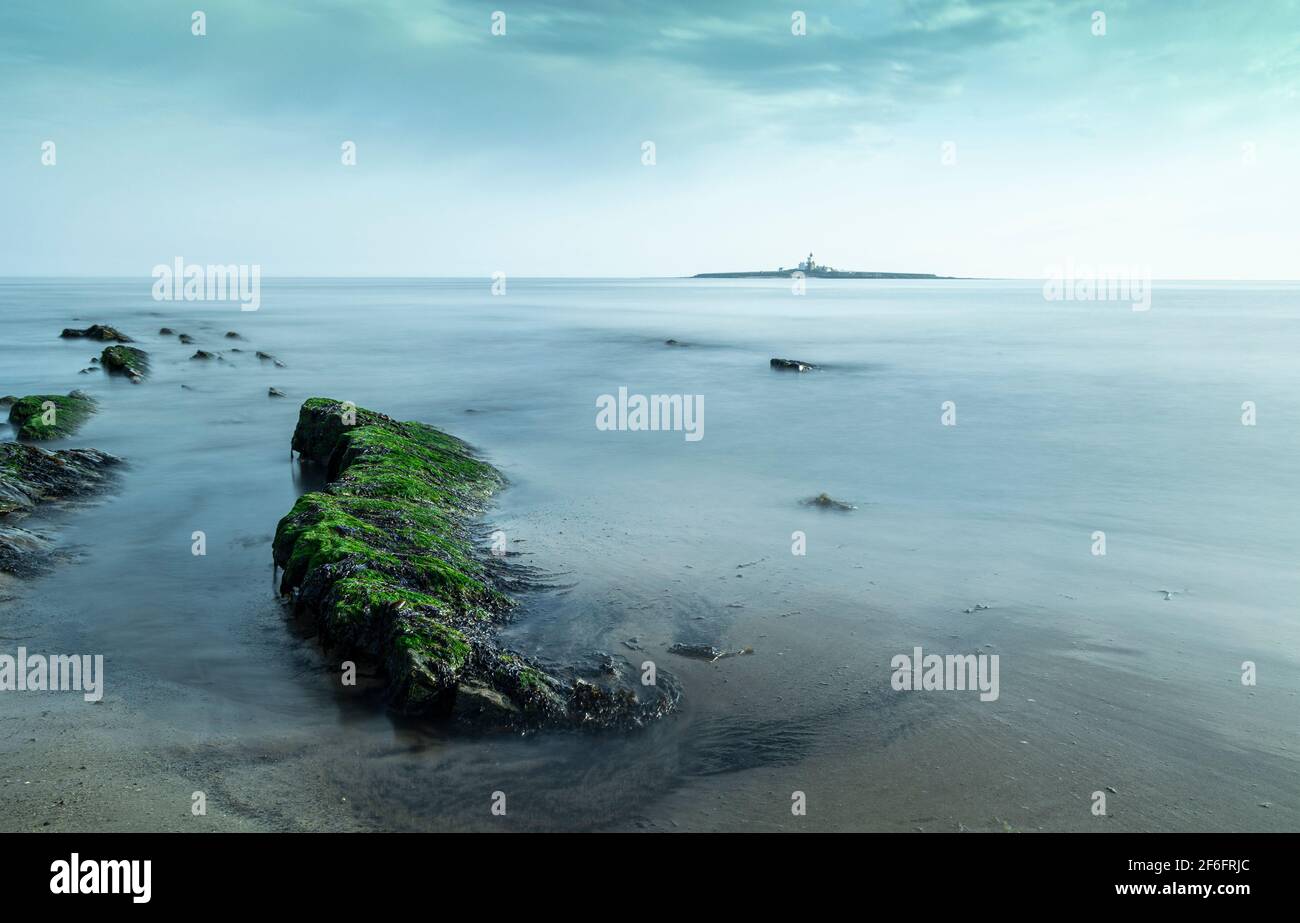 Long exposures of Coquet Island using exposed rocks as leading lines Stock Photo