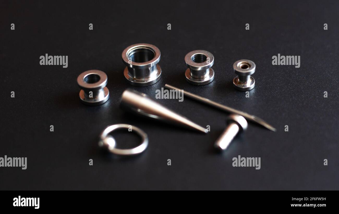 Set for piercing on a dark background, ear tunnels, tunnels and earrings for the ears and tongue