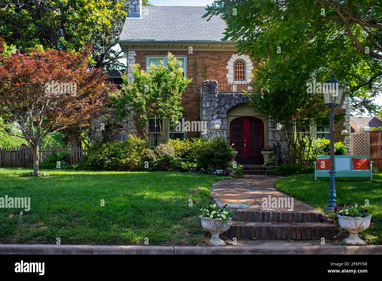 Beautiful upscale house with rock castle like entrance and retro metal lounger  and little rabbit in front yard - curb appeal Stock Photo