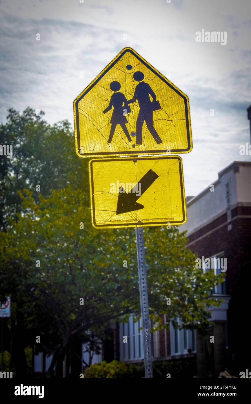 Closeup of old grungy chilren-students walk here sign with cracks outside out school building with trees Stock Photo