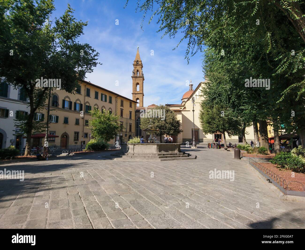 Calm small square with fountain, cobblestone and bell tower surrounded with green trees in center of old Florence city, travel Italy Stock Photo