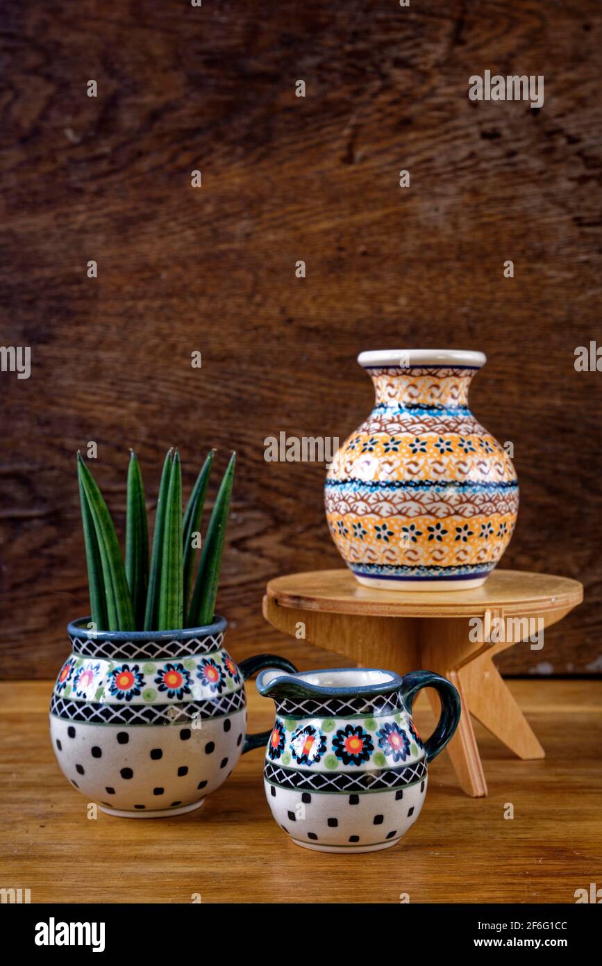 Set of hand made and painted porcelain tableware made in Poland. Bolesławiec pottery on wooden rustic background. Polish craft, culture and pottery Stock Photo