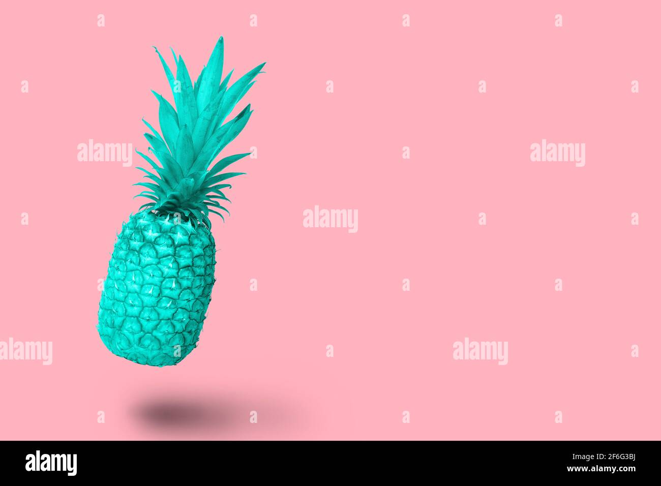 Design turquoise blue pineapple fruit floating on a pink background Stock Photo