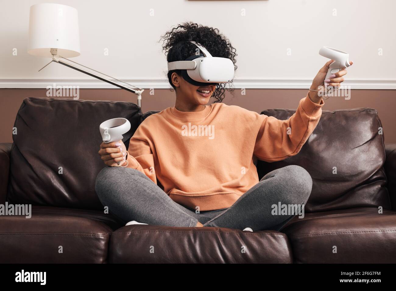 Woman with joysticks and VR goggles playing video games Stock Photo