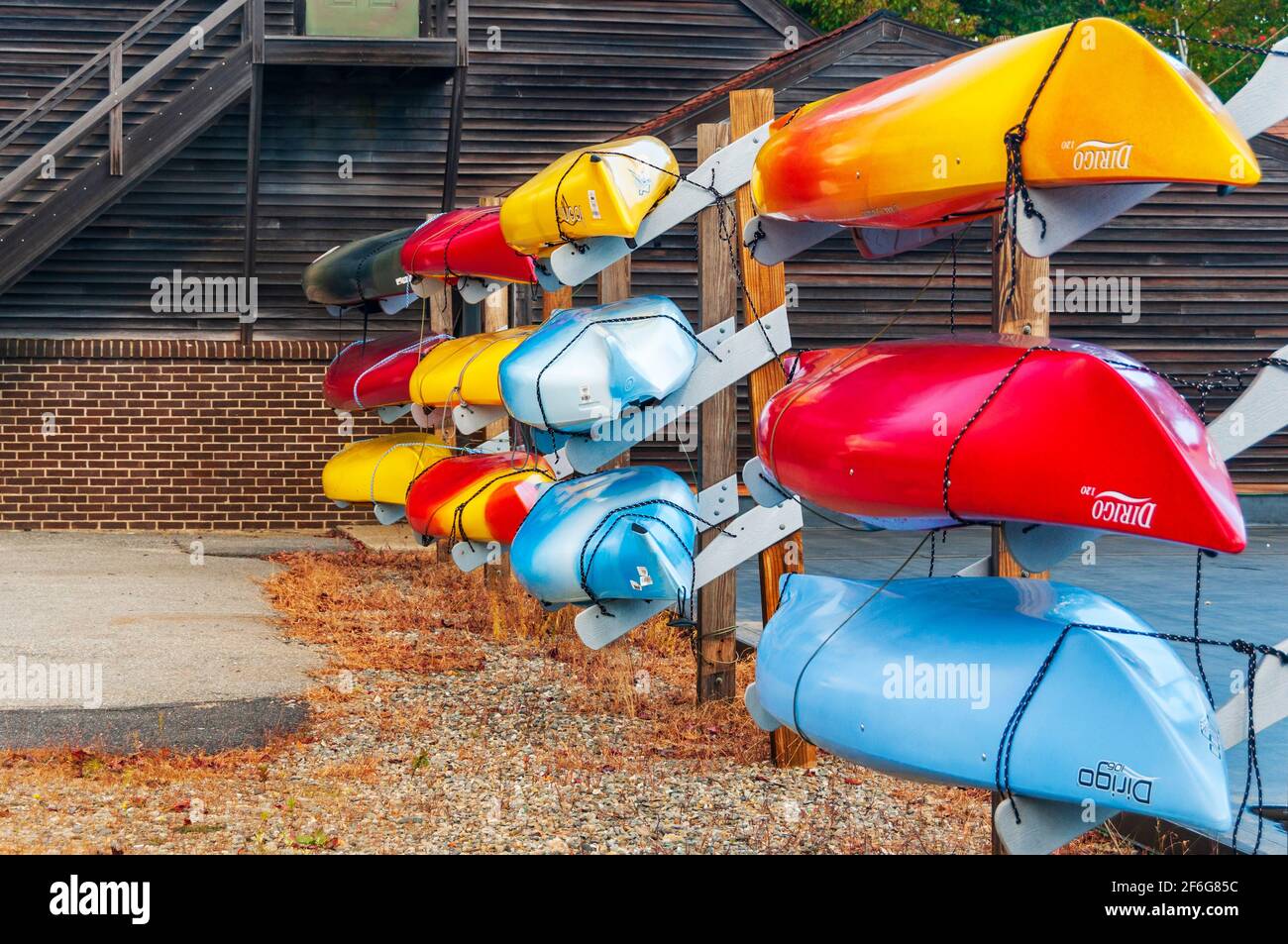 A rack of colorful blue, red and yellow kayaks for rental or sale in New England, USA. Stock Photo
