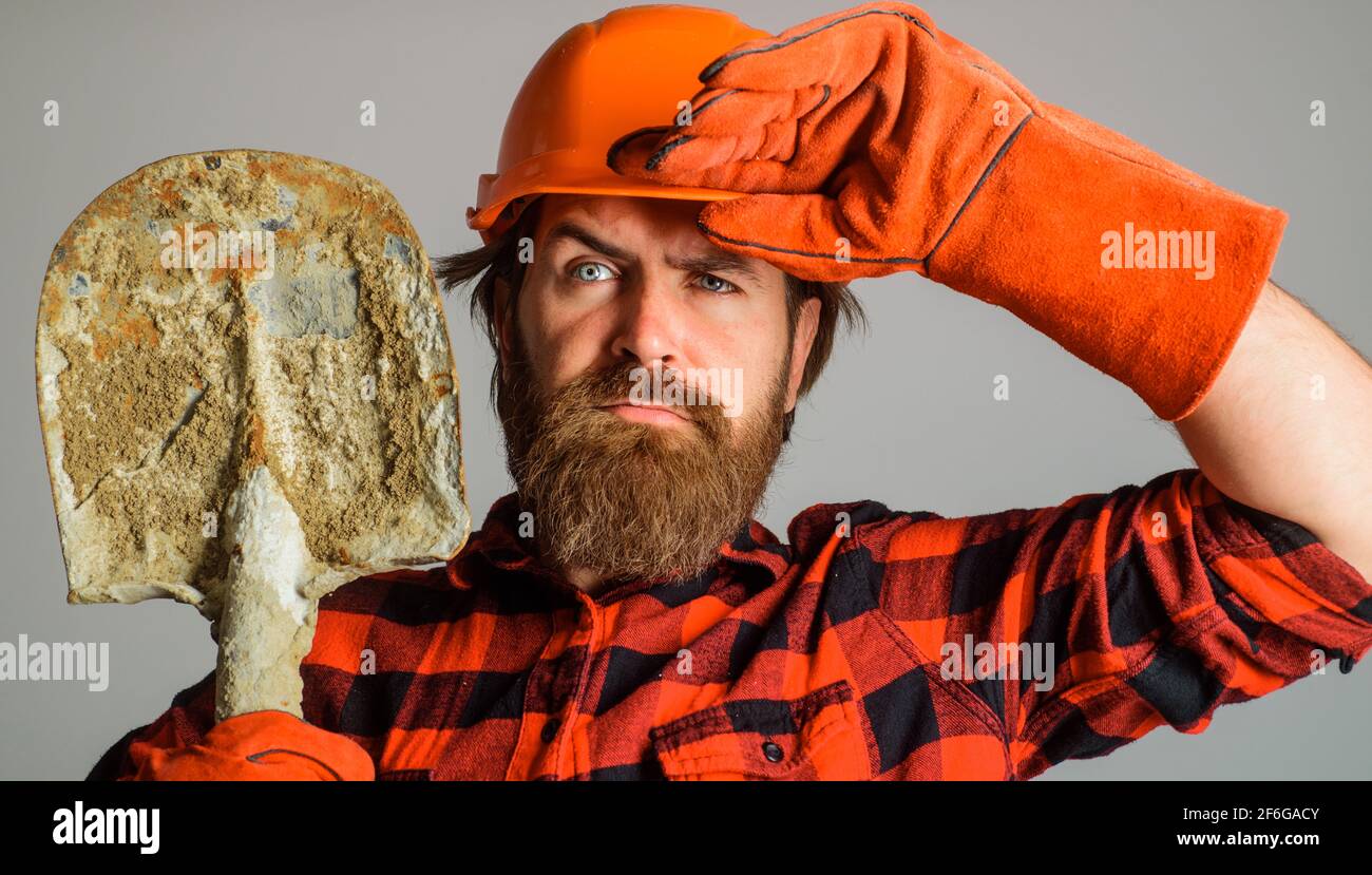 Builder in hard hat and work gloves with shovel. Workman with spade ...