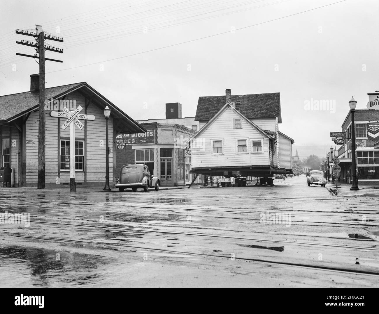 House being moved through the main street of town (population 2473). Deposited over Sunday on intersection of U.S. 99. Quiet, rainy afternoon. Cottage Grove, Lane County, Oregon. 1939.  Photograph by Dorothea Lange. Stock Photo