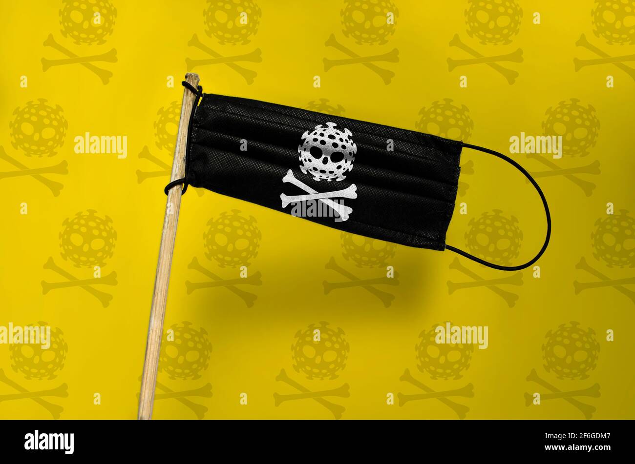The medical mask flies pirate a flag on a pole with COVID skull and bones. Black mask on yellow textured background. Black pirate virus Attack flag. C Stock Photo