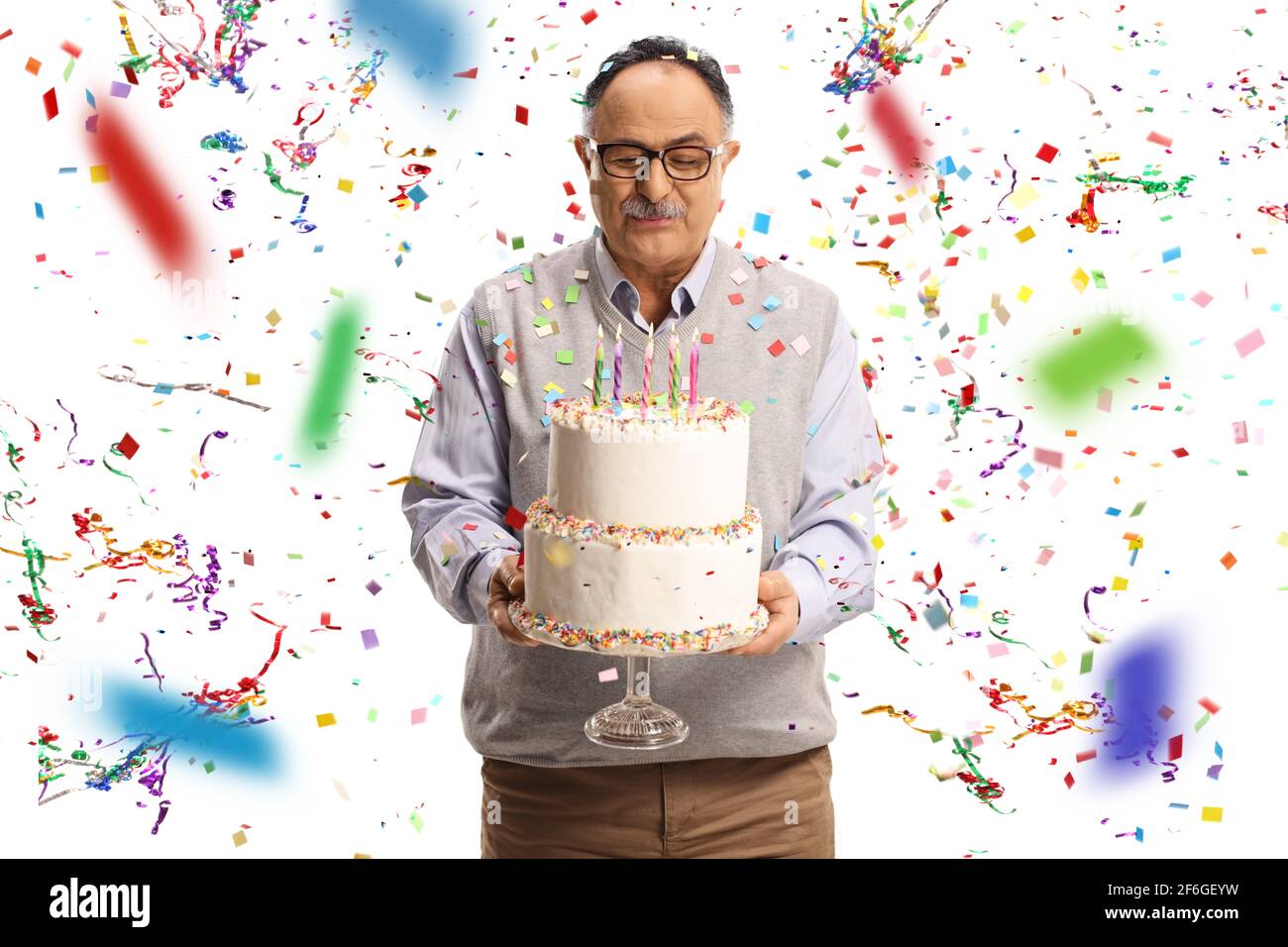 Elderly man holding a birthday cake with confetti flying around