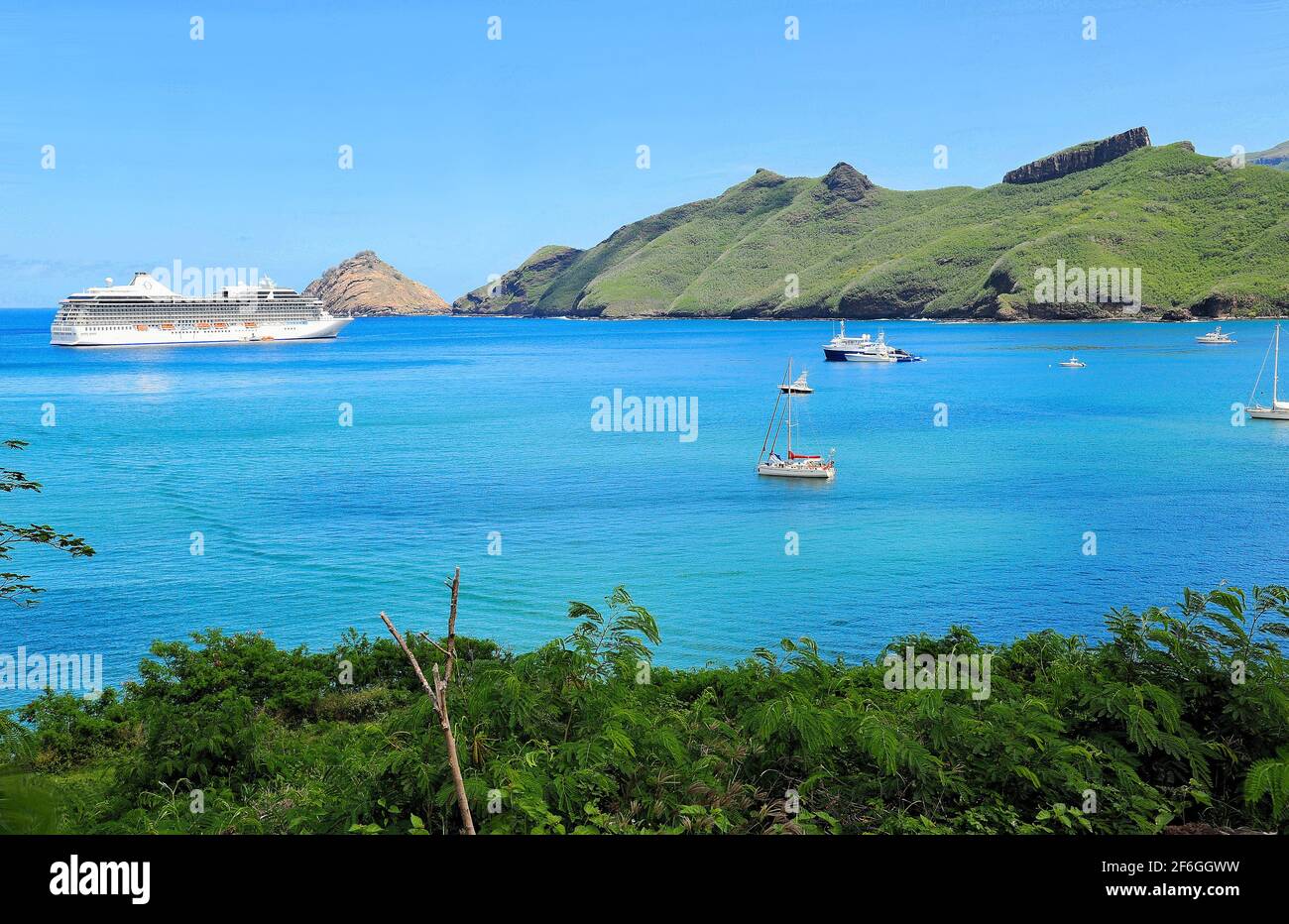 A cruise ship cruising the Polynesian Islands lies anchored in the warms waters of the Pacific Ocean near an island of French Polynesia. Stock Photo