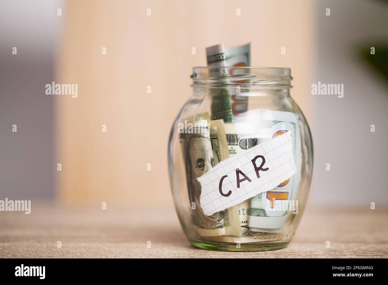 Dollar bills in glass jar and text car on wooden table Stock Photo