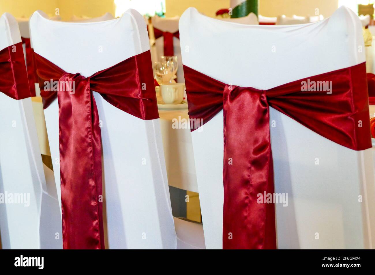 White chair covers with red bows. Decoration for wedding or birthday,  close-up Stock Photo - Alamy